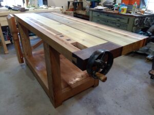 Just finished my workbench. Not Paul's design, but used several of his techniques in building it. At 69 years old I have learned so much from watching his videos and am teaching my 15 year old grandson all I can. All joints are mortise and tenon using Oak dowels to draw pin them together. Wood was all material I have accumulated over the past 40 years, Poplar, Cherry, Black Walnut, Oak and Spruce. Thought Paul would appreciate some of the "upcycling" I did on the vises, using old horse drawn machinery parts.