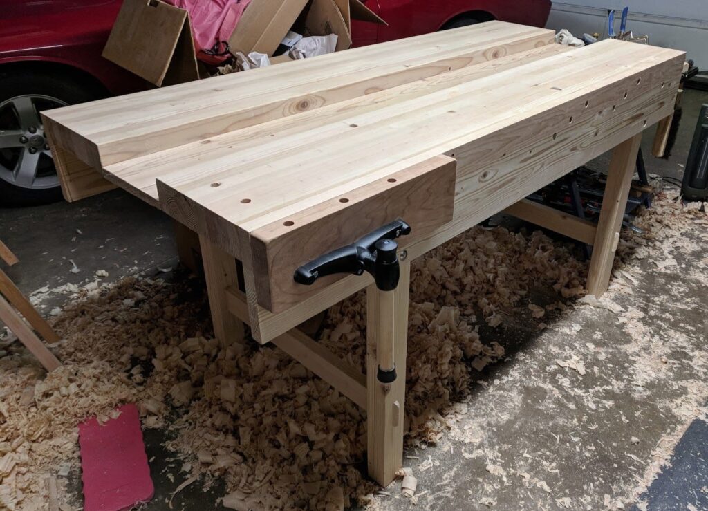 Made from cheap Home Depot douglas fir 2x4s, with the exception of the vise that's cherry. The legs on the end with the vise are a bit further from the end for clearance (14"), and the well is only 9.5" wide, but otherwise pretty much exactly like the older YouTube videos.