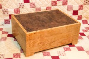 Made from Cherry with a two way bookmatched burr Walnut veneer panel on the lid, surrounded by Boxwood stringing. Finish is Danish oil